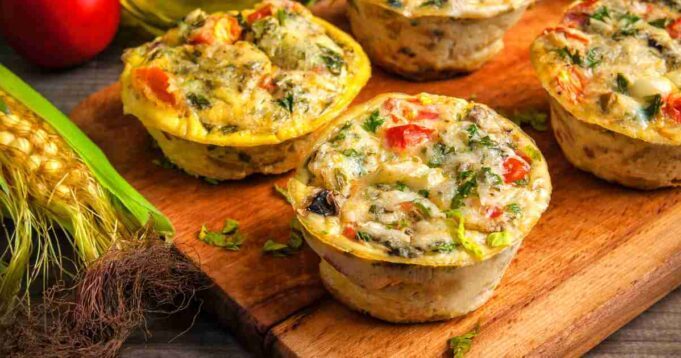 Golden-brown savory breakfast muffins filled with vegetables and cheese on a cooling rack