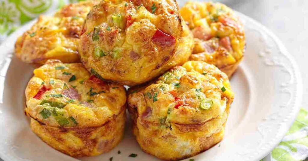 Golden-brown savory breakfast muffins filled with vegetables and cheese on a cooling rack. savory breakfast muffins Savory Breakfast Muffins Breakfast Muffins recipe2 1024x538
