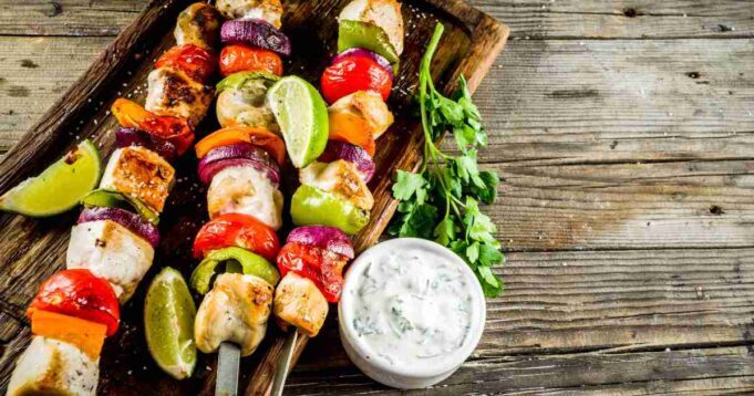 Juicy chicken and lemon skewers on a grill, with vibrant lemon slices and herbs.