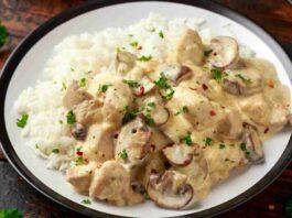 A skillet filled with creamy chicken and mushrooms garnished with fresh herbs.