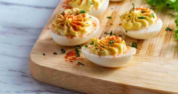 A platter of creamy deviled eggs garnished with paprika and fresh herbs.