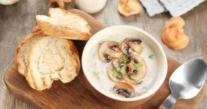 A close-up of creamy mushrooms on golden-brown toast garnished with fresh herbs.