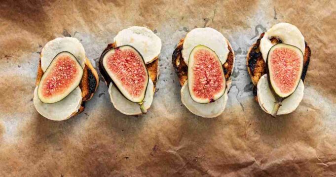 A rustic and elegant serving of Figs on Toast with creamy Goat’s Yogurt Labneh, garnished with fresh herbs and drizzled with honey.