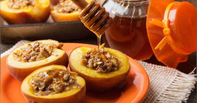 Honey-glazed pears topped with a golden nut mixture on a rustic white plate.