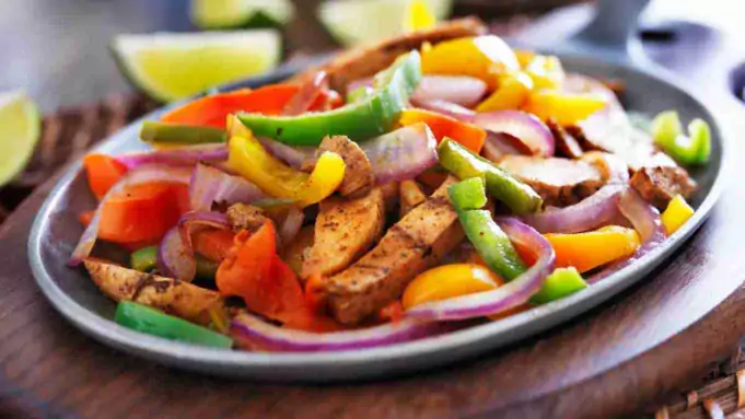 Colorful and appetizing Sheet Pan Chicken Fajita Bowls served on a white plate.