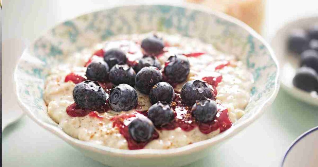 Creamy porridge in a bowl topped with a rich, purple-hued blueberry compote and a sprinkle of almonds. porridge with blueberry compote Porridge with Blueberry Compote Porridge with Blueberry Compote 1024x538