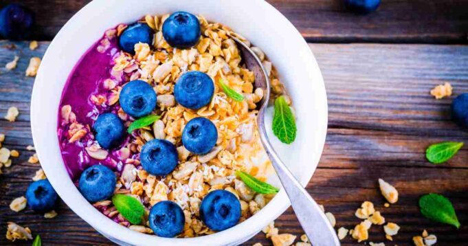 Creamy porridge in a bowl topped with a rich, purple-hued blueberry compote and a sprinkle of almonds.