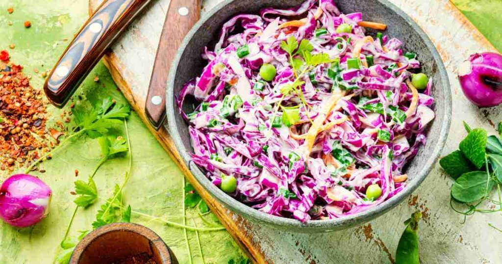 A vibrant bowl of Spicy Cabbage Slaw, bursting with colours of red and green cabbage, carrots, and a tangy dressing. spicy cabbage slaw Spicy Cabbage Slaw Spicy Cabbage Slaw1 1024x538