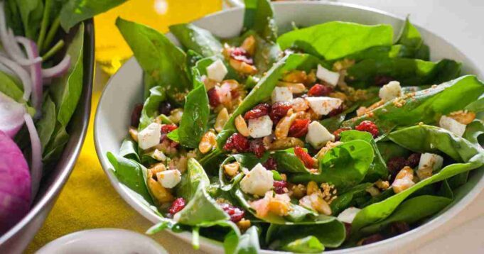 This is a fresh and colorful spinach salad with a glistening homemade vinaigrette dressing, garnished with eggs, nuts, and cheese.