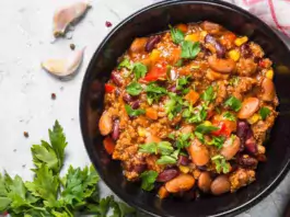 A bowl of hearty and healthy chilli con carne garnished with fresh herbs.