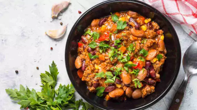 A bowl of hearty and healthy chilli con carne garnished with fresh herbs.