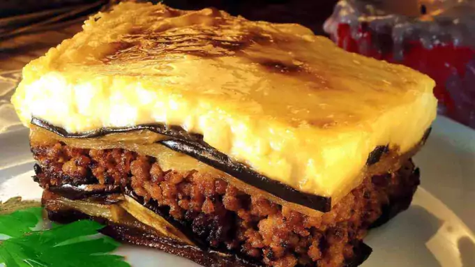 A healthy and delicious serving of low-fat moussaka with layers of eggplant, meat sauce, and creamy topping on a white plate.