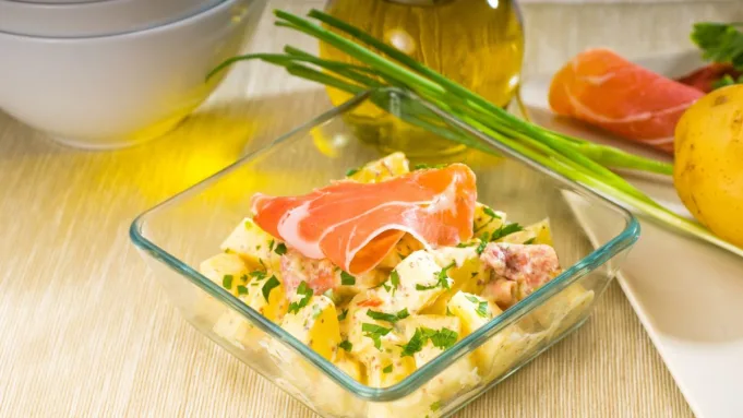 Succulent slices of Parma Pork served with a creamy and vibrant potato salad on a rustic plate.
