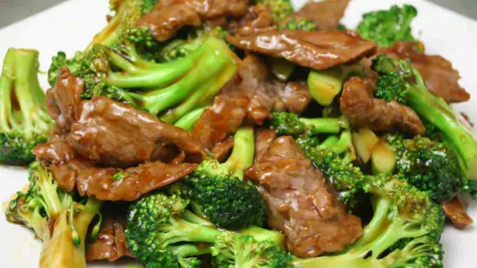 Succulent beef and vibrant green broccoli in a savoury sauce, served in a white pot.